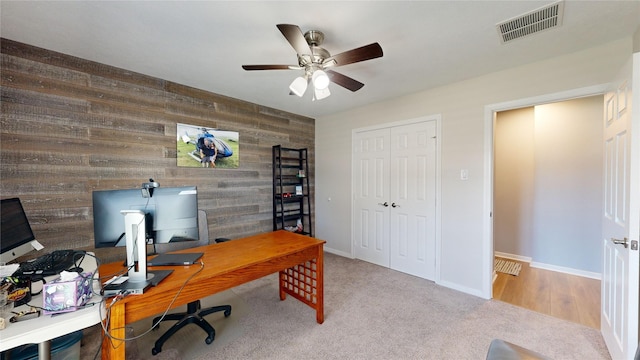 office area featuring ceiling fan, light colored carpet, and wooden walls