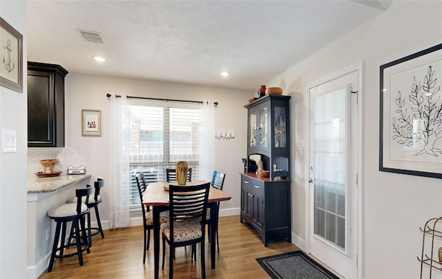 dining space featuring a textured ceiling and light wood-type flooring