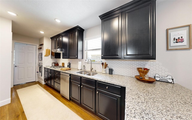 kitchen featuring appliances with stainless steel finishes, sink, light hardwood / wood-style flooring, and backsplash