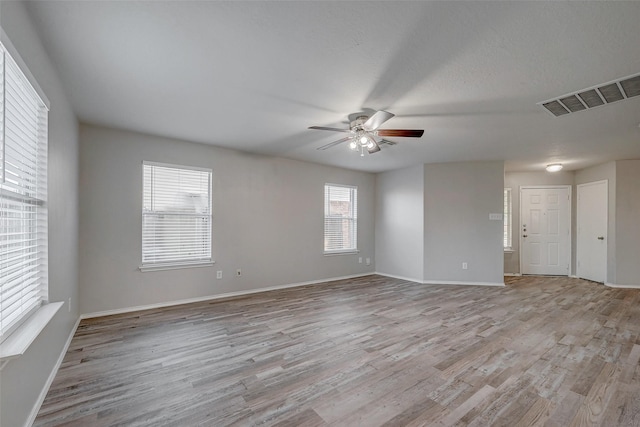 unfurnished room with a textured ceiling, light hardwood / wood-style floors, and ceiling fan