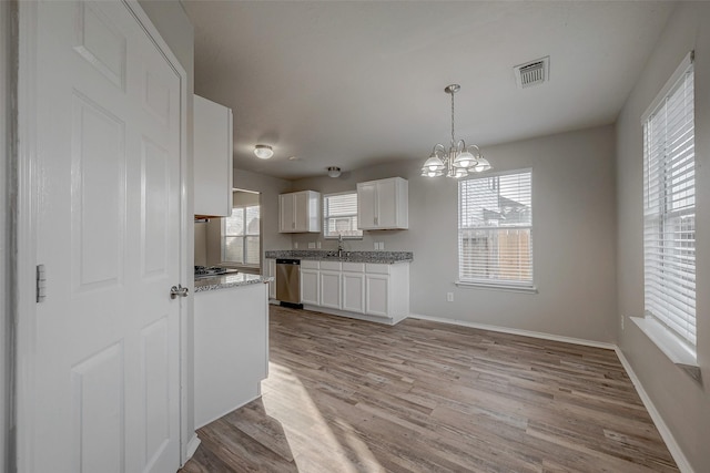 kitchen with appliances with stainless steel finishes, pendant lighting, white cabinets, a notable chandelier, and light wood-type flooring