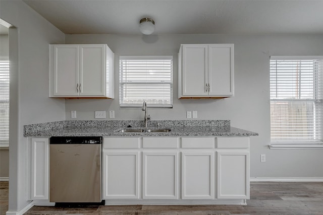 kitchen featuring white cabinetry, stainless steel dishwasher, sink, and light stone counters