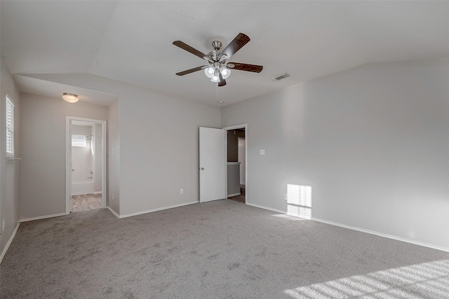 carpeted spare room featuring ceiling fan and vaulted ceiling