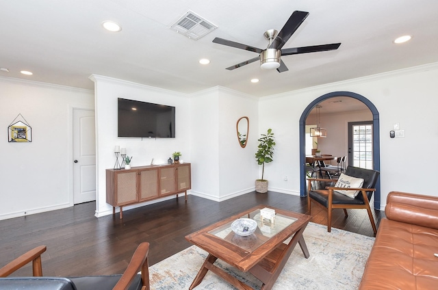 living room with ornamental molding, dark wood-type flooring, and ceiling fan