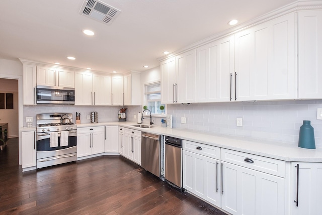 kitchen featuring sink, appliances with stainless steel finishes, dark hardwood / wood-style floors, decorative backsplash, and white cabinets