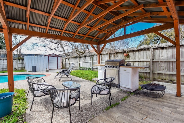 view of patio / terrace with a fire pit, grilling area, and a storage unit