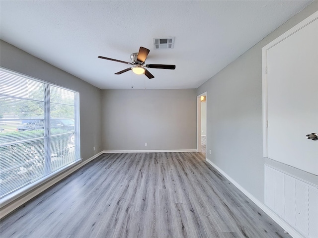 spare room with a textured ceiling, light hardwood / wood-style flooring, and ceiling fan