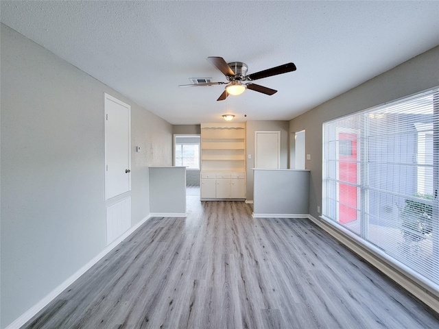 unfurnished room with ceiling fan, light hardwood / wood-style flooring, and a textured ceiling