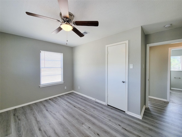 unfurnished bedroom with ceiling fan, light hardwood / wood-style flooring, and a textured ceiling