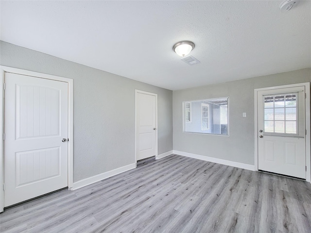 foyer with light hardwood / wood-style floors and a textured ceiling