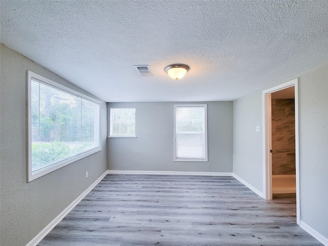 empty room with light hardwood / wood-style flooring and a textured ceiling