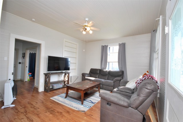 living room with hardwood / wood-style floors, built in features, and ceiling fan