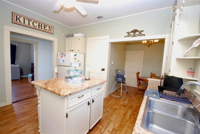 kitchen featuring white refrigerator, light hardwood / wood-style floors, sink, and white cabinets