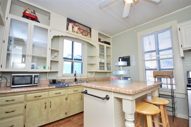 kitchen featuring sink, a breakfast bar area, ceiling fan, light hardwood / wood-style floors, and cream cabinets