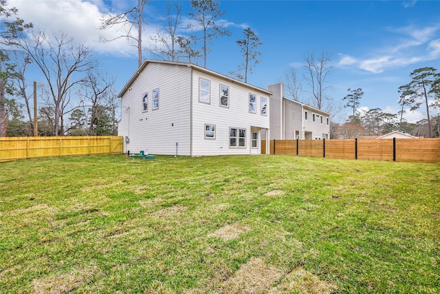 rear view of house featuring a fenced backyard and a yard