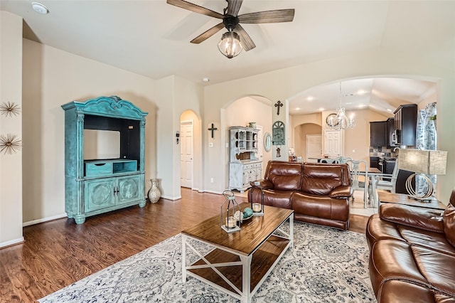 living room featuring dark wood-type flooring and ceiling fan with notable chandelier