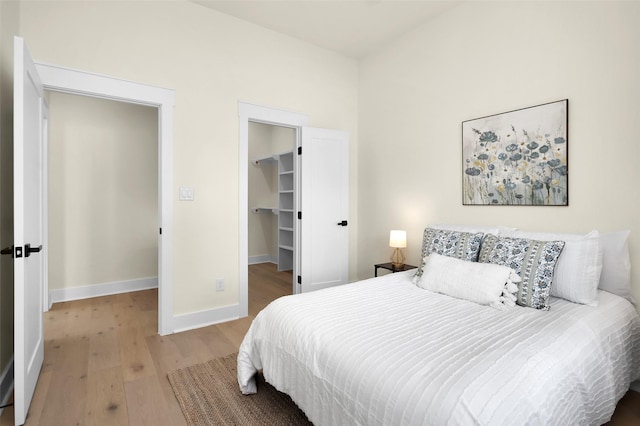 bedroom with a spacious closet, light hardwood / wood-style flooring, and a closet