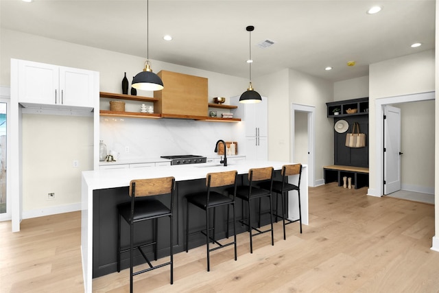 kitchen featuring hanging light fixtures, backsplash, and white cabinets