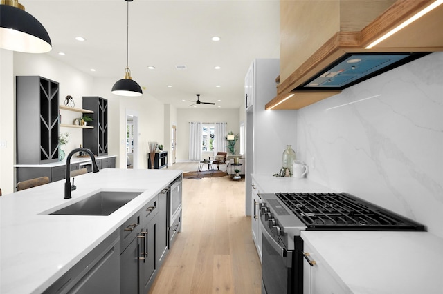 kitchen with sink, custom exhaust hood, gray cabinetry, appliances with stainless steel finishes, and pendant lighting