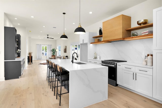 kitchen featuring white cabinetry, gas stove, hanging light fixtures, and sink