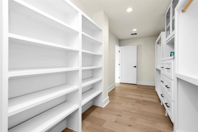 walk in closet with light hardwood / wood-style flooring