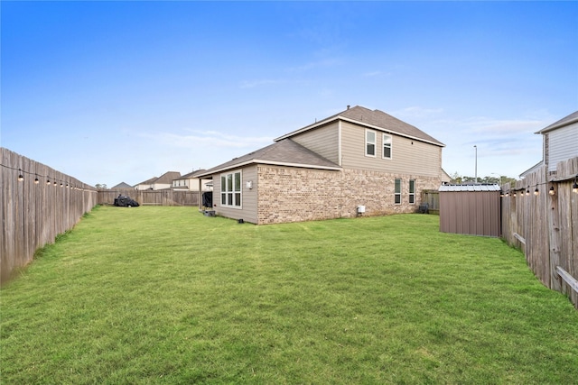 rear view of house with a yard and a storage unit