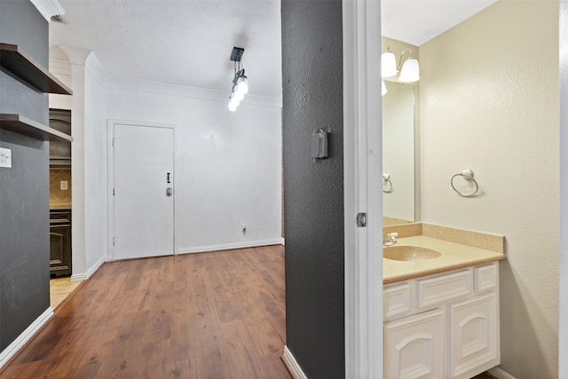 bathroom with hardwood / wood-style flooring, ornamental molding, and vanity