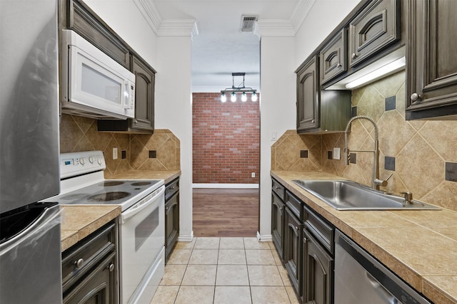 kitchen featuring stainless steel appliances, ornamental molding, sink, and light tile patterned floors