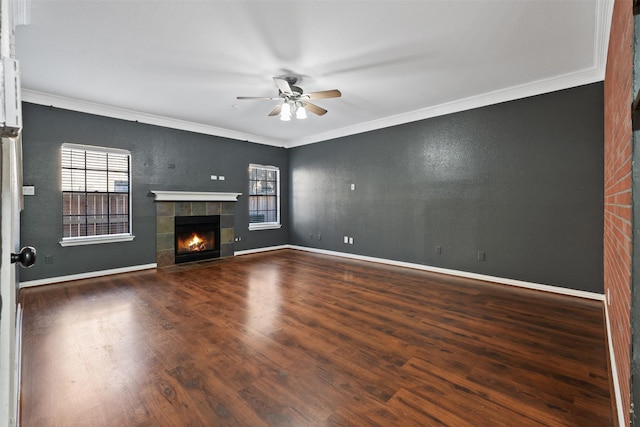 unfurnished living room featuring crown molding, ceiling fan, dark hardwood / wood-style floors, and a tiled fireplace