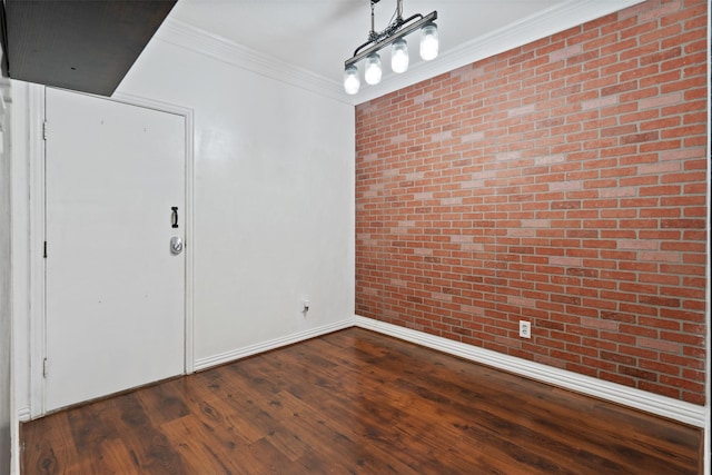 empty room with dark wood-type flooring, ornamental molding, and brick wall