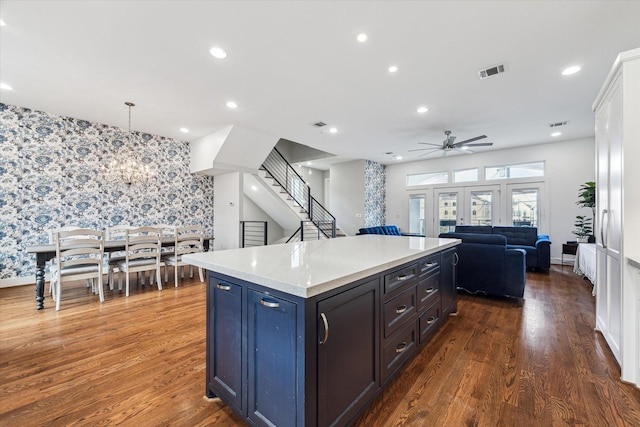 kitchen with dark hardwood / wood-style flooring, hanging light fixtures, ceiling fan with notable chandelier, and a kitchen island