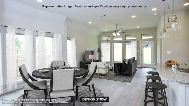 dining room featuring ceiling fan, sink, a wealth of natural light, and light wood-type flooring