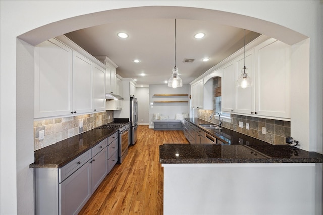 kitchen featuring sink, decorative light fixtures, kitchen peninsula, stainless steel appliances, and white cabinets