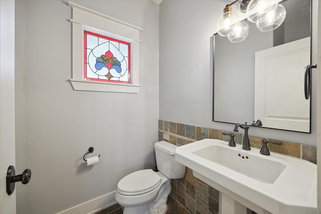 bathroom featuring toilet, sink, and tile walls