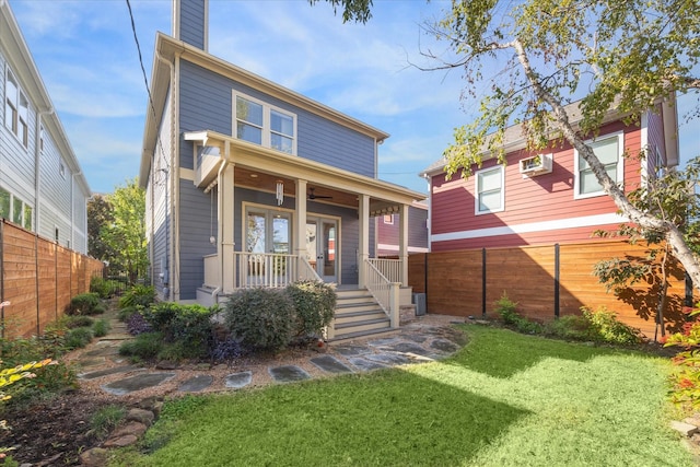 view of front of property featuring a porch, a wall mounted air conditioner, and a front yard