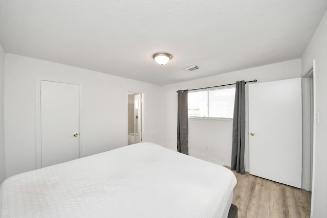 bedroom with light hardwood / wood-style flooring and a textured ceiling
