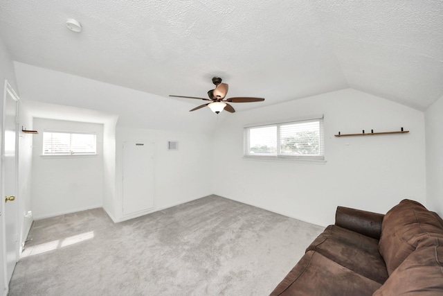 unfurnished living room with ceiling fan, light colored carpet, vaulted ceiling, and a textured ceiling