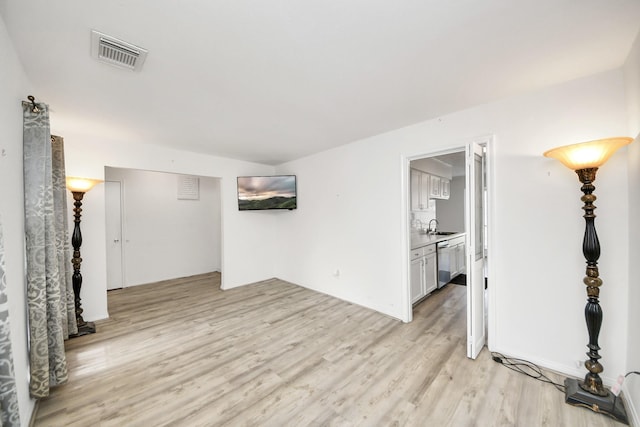 unfurnished living room featuring sink and light hardwood / wood-style floors