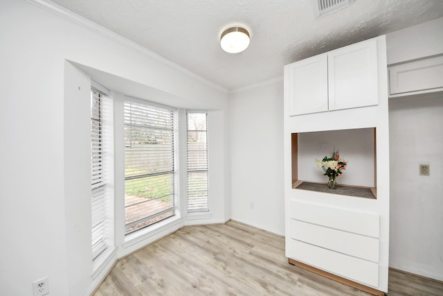 interior space featuring crown molding, light hardwood / wood-style flooring, and a textured ceiling