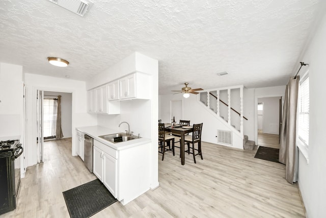 kitchen with gas stove, dishwasher, sink, and white cabinets