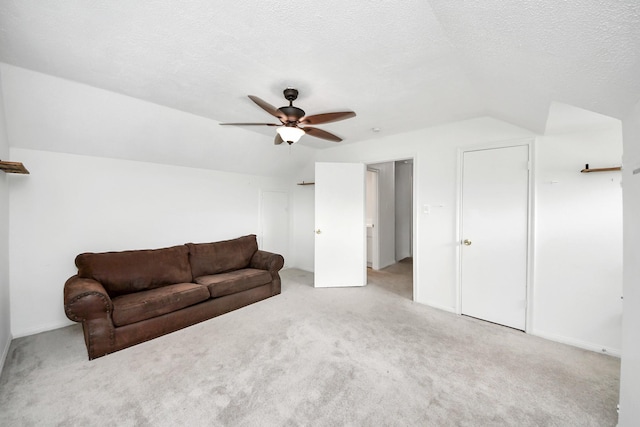 unfurnished living room featuring light carpet, ceiling fan, vaulted ceiling, and a textured ceiling