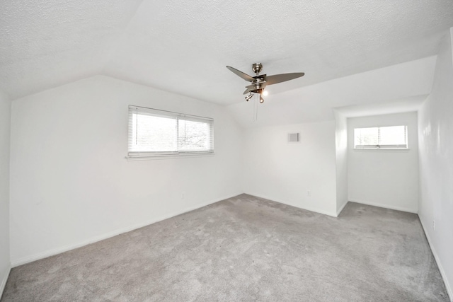 bonus room with ceiling fan, lofted ceiling, light colored carpet, and a textured ceiling
