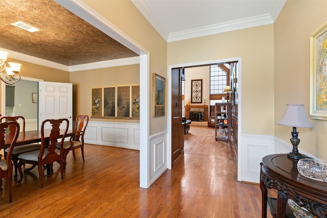 7315 Muirfield Valley Dr, Houston, TX 77095 - dining area with crown molding, wainscoting, a decorative wall, a chandelier, and wood finished floors