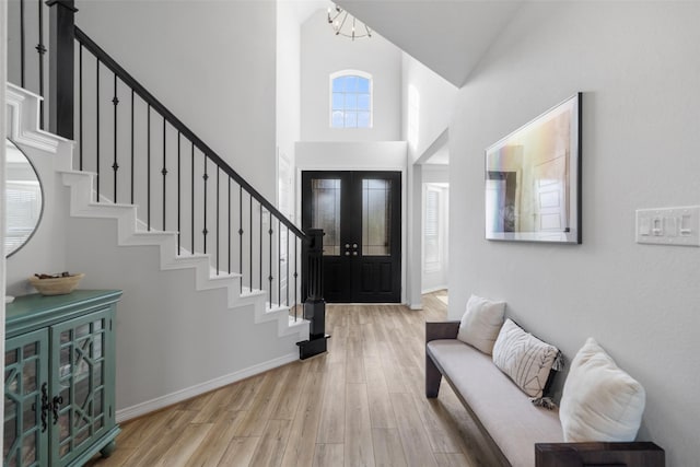 entrance foyer featuring light hardwood / wood-style flooring, high vaulted ceiling, and french doors