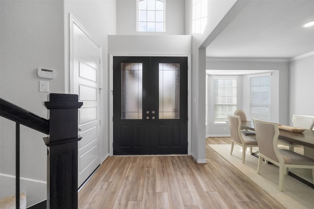 foyer featuring crown molding, a healthy amount of sunlight, and light hardwood / wood-style flooring