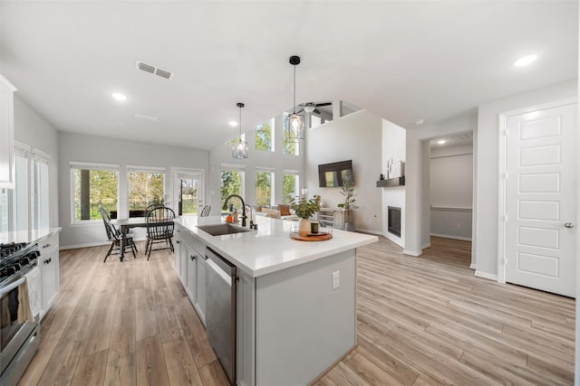 kitchen featuring pendant lighting, sink, a kitchen island with sink, light hardwood / wood-style floors, and stainless steel appliances