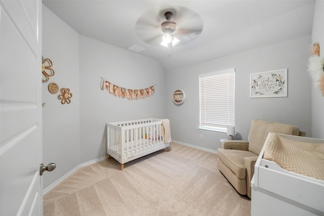 bedroom featuring vaulted ceiling, a nursery area, light colored carpet, and ceiling fan