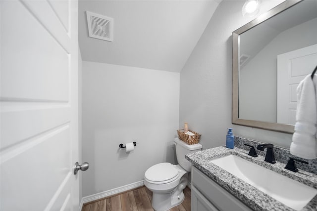 bathroom with lofted ceiling, vanity, wood-type flooring, and toilet