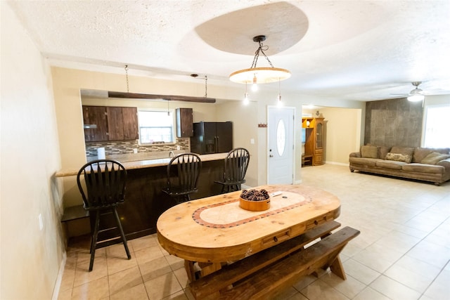 dining room featuring light tile patterned flooring, a healthy amount of sunlight, and a textured ceiling