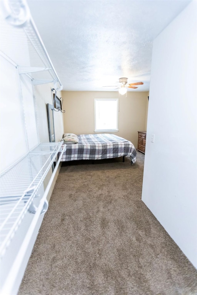 unfurnished bedroom featuring ceiling fan, carpet floors, and a textured ceiling